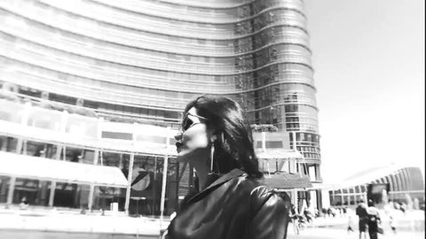 Raphaella Ferrari in leather jacket by Milan tower, profile view