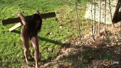 Nude Asian woman bound to wooden cross outdoors in Insex Cabin BDSM