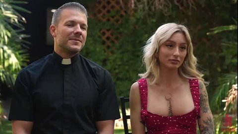 Blonde Kathryn Mae with priest in revealing red dress outdoors