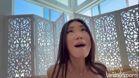 Lucy Mochi smiling topless in sunny room, big tits exposed