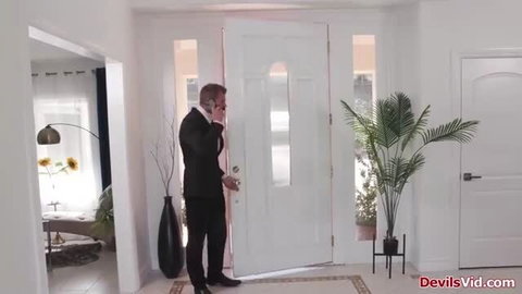 Adira Allure as suited housekeeper at door on phone