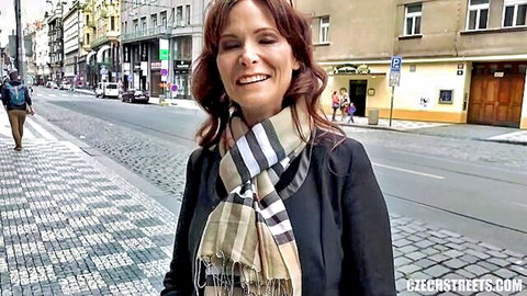 Smiling mature redhead MILF in scarf posing on public Prague street