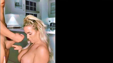 Blonde MILF topless in kitchen, hands caressing her large breasts and body