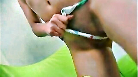 Slim Asian woman teasing with panties, exposing midriff in green bikini