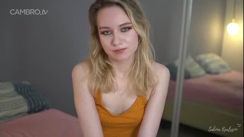 Sab Karllson blonde cam girl in orange tank top, teasing cleavage