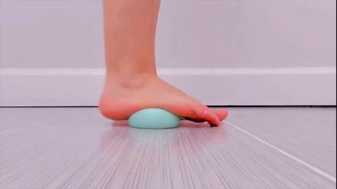 Slim Asian girl barefoot foot massage with green ball, sexy sole stretch