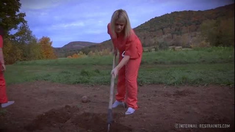 Blonde prisoner Harley Ace digs grave in chains outdoors bondage