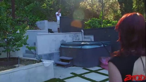 Redhead in black halter top by hot tub, guy watches from above in Satisfying Nikki