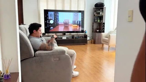Richiesummer lounging shirtless on couch watching TV in luxury home