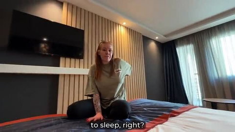 Busty redhead tattooed stepmom sits on bed in t-shirt, ready for taboo hotel fuck