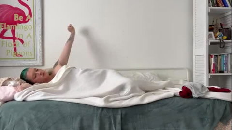 Pregnant green-haired woman waking up nude in bed stretching