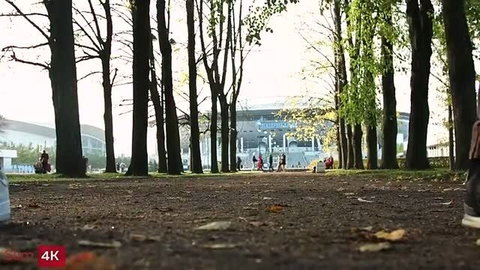 Lana Roy at stadium park path, trees and crowds, fall day outdoor view