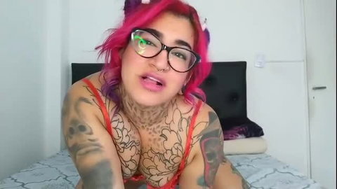 Pink-haired tattooed alt girl in red lace bra teases on bed