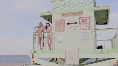 Two nude all-natural hotties topless on beach lifeguard tower