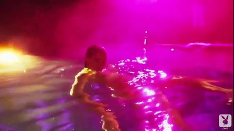 Busty babe naked and wet in neon-lit pool, soapy curves glistening