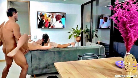 Muscular guy fucks slim brunette GF on couch while he watches TV