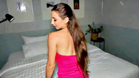 Brunette in tight pink dress, long hair, seductive back view in bedroom