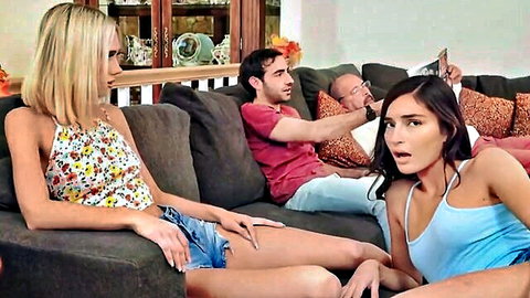 Shocked blonde and brunette sisters with stepbrothers on couch