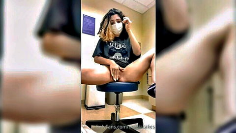 Curly-haired woman masturbating in doctor's office, legs spread wide exposing pussy