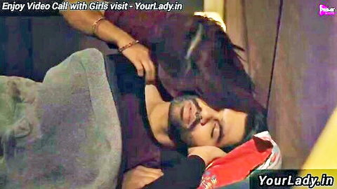 Sexy Indian woman leaning over sleeping man's chest in intimate bed tease