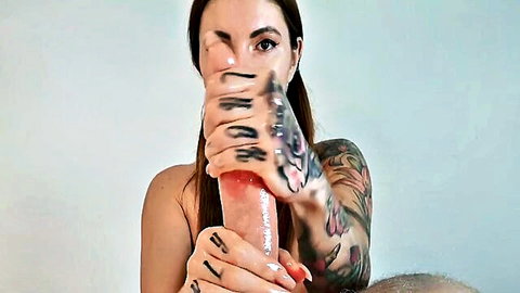 Tattooed brunette with long hair stroking large pink dildo close-up