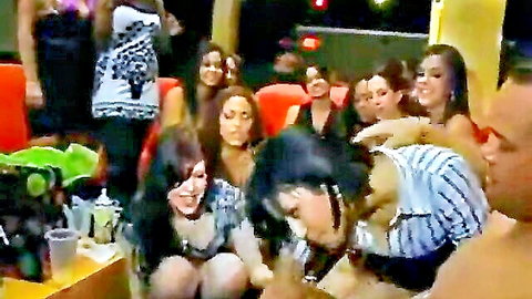 Sexy Latinas in skimpy tops crowd around shirtless muscular stud at wild neon-lit party
