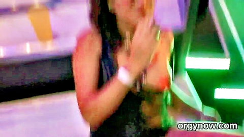 Brunette with huge cleavage in tight black top dancing under neon club lights