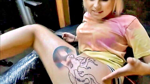 Smiling blonde girl showing fresh octopus thigh tattoo in non-nude PMV