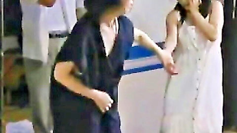 Busty Japanese woman in black dress with deep cleavage grabs surprised Asian girl in white sundress