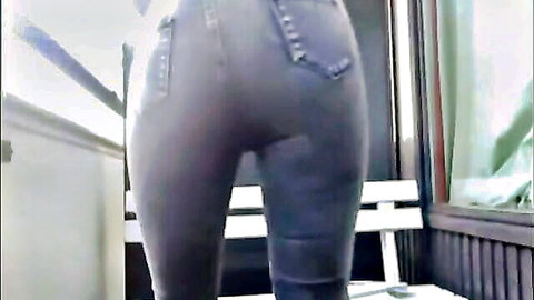 Curvy woman bending over in tight gray jeans, showcasing big ass outdoors