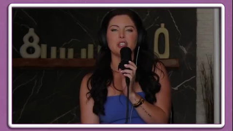 Theodora Day sings into mic in tight blue tube top, sultry look