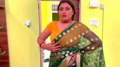 Indian woman in green polka dot saree and yellow blouse posing in doorway