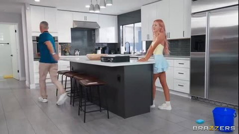 Kenzie Taylor in yellow top and blue skirt leaning on kitchen island