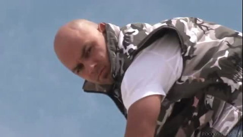 Rocco Siffredi in camouflage vest looking down at camera