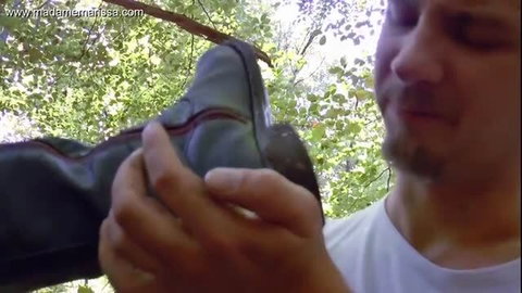 Woman in riding boots dominates slave in forest boot worship scene
