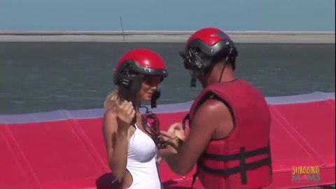 Blonde in white swimsuit and red life vest on beach boat
