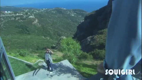 Woman posing on scenic cliff overlooking ocean and hills