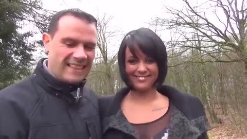 Brunette MILF with short black hair outdoors in woods smiling with man