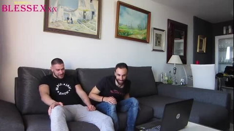Zeus Ray in black t-shirt sitting on couch with another man