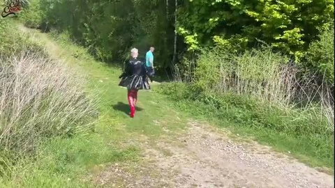 Woman in black outfit and red stockings walking on outdoor path