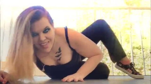 Plus-size model with blonde hair posing seductively on floor in black top