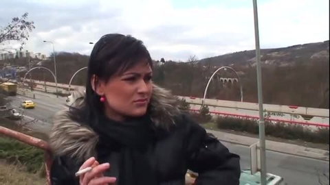 Brunette woman in winter coat outdoors, smoking
