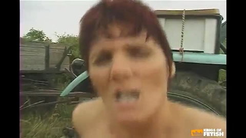 Mature short-haired redhead woman distressed face close-up outdoor tractor scene