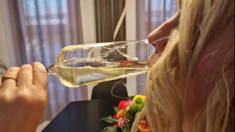 Blonde woman drinking champagne from bottle held by man