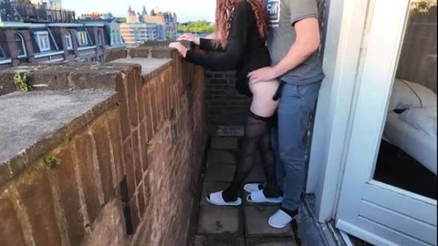 Couple having sex on balcony, woman in stockings bent over