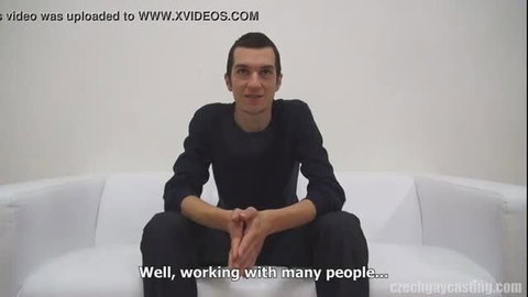 Caleb Moreton in black shirt on white couch, Czech Gay Casting interview
