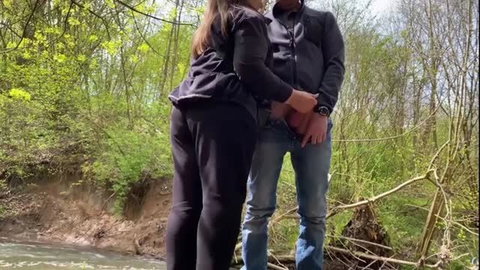 Woman jerking man's cock outdoors by the river