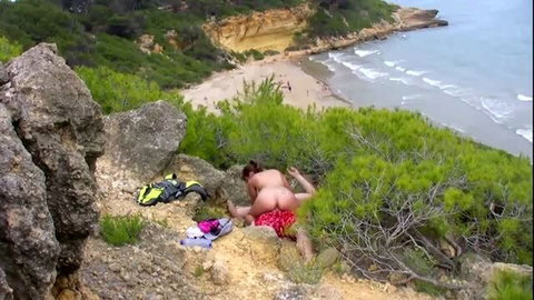 Couple having outdoor sex on rocks overlooking a secluded beach