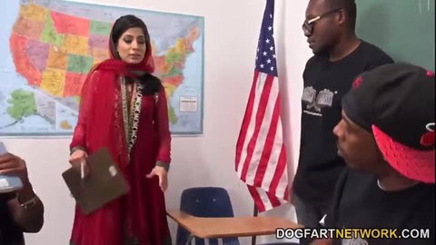 Nadia Ali in red dress surrounded by black men in classroom setting