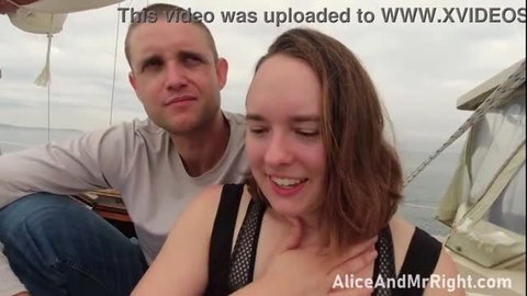Couple embracing on a boat, woman in black mesh top smiling with man's hand on her chest